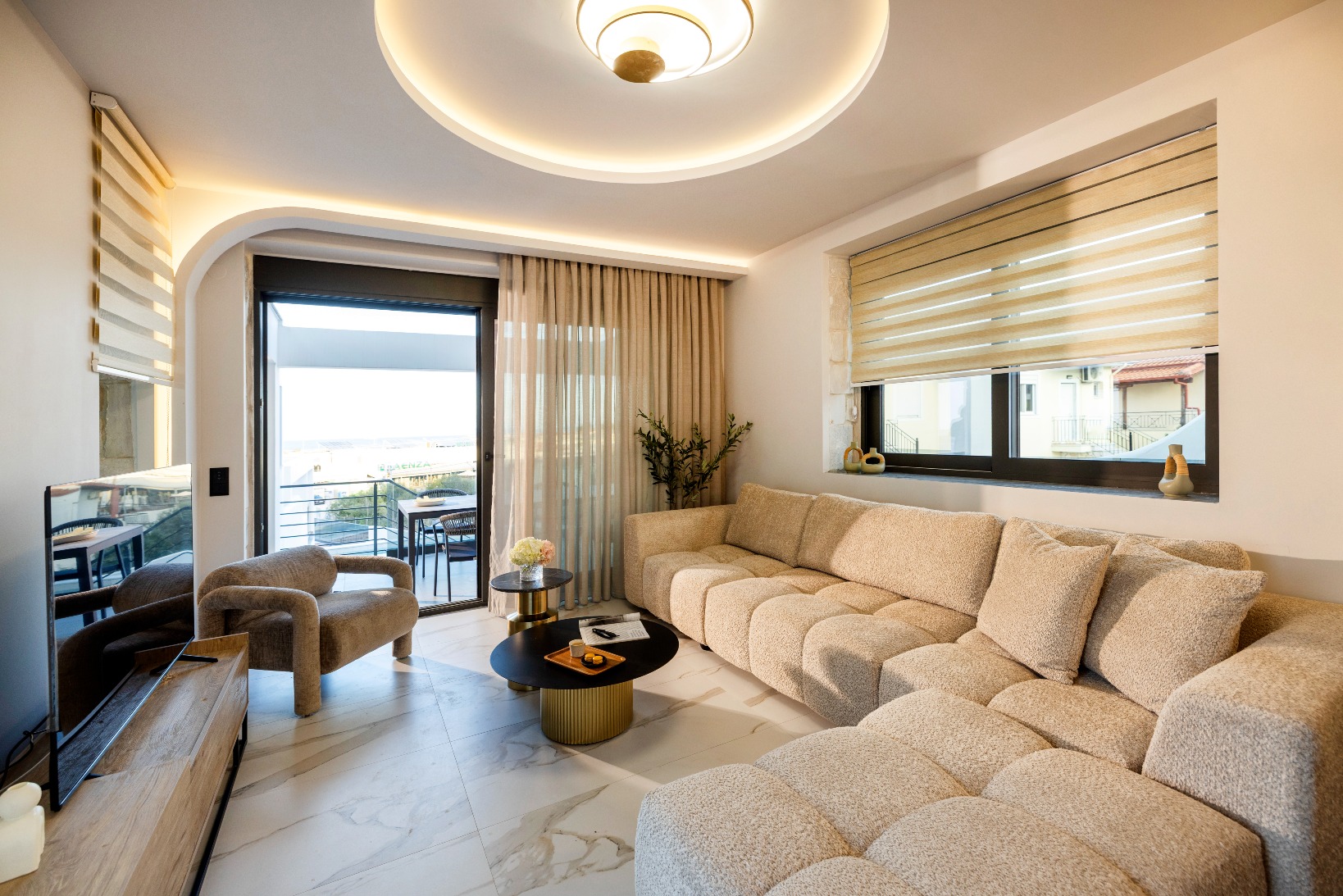 Contemporary living room with beige sectional sofa, marble flooring, and balcony view.